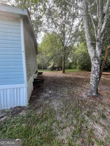 a view of a backyard with large trees and wooden fence