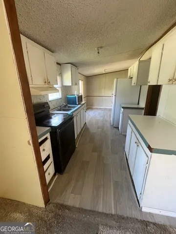 a kitchen with granite countertop a sink a stove top oven a counter space and cabinets