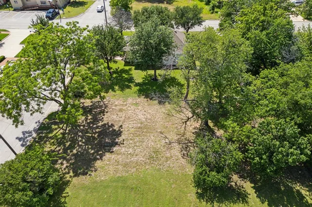 an aerial view of residential houses with outdoor space and trees