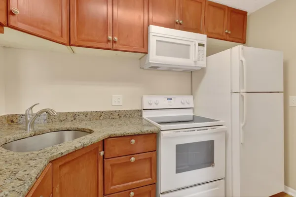 a kitchen with granite countertop a sink stove and refrigerator