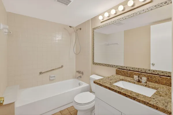 a bathroom with a granite countertop sink a toilet and a bathtub