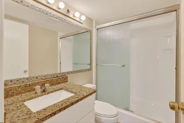 a bathroom with a granite countertop sink mirror and a shower