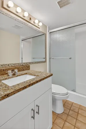 a bathroom with a granite countertop sink mirror vanity and toilet