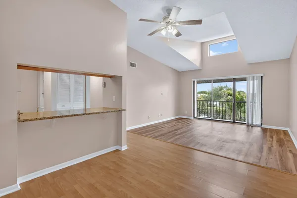 an empty room with wooden floor fan and windows