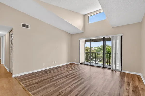 a view of an empty room with wooden floor and a window
