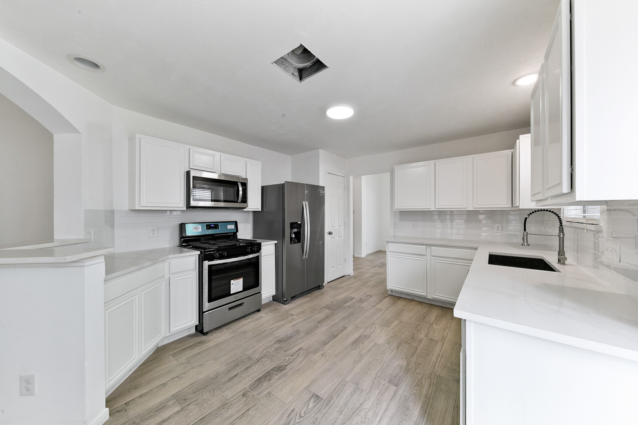12014 Raven View Drive Houston, TX 77067 - Photo 27 of 29 This modern kitchen features sleek white cabinetry, stainless steel appliances, and wood-look flooring. The spacious layout offers plenty of counter space and a stylish, minimalist design perfect for any homebuyer.