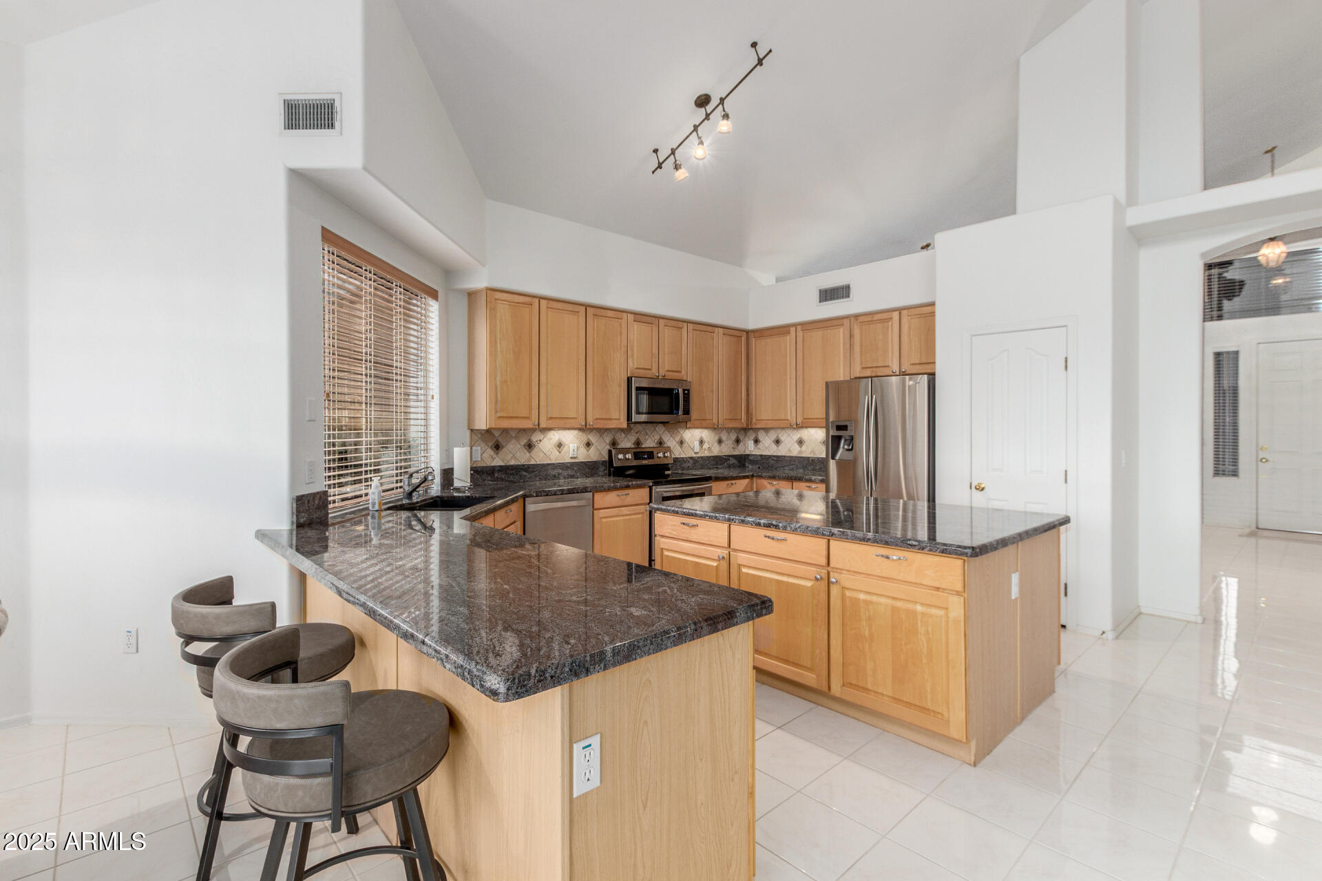 1111 South Sandstone Street Gilbert, AZ 85296 - Photo 14 of 59 a kitchen with stainless steel appliances granite countertop a stove top oven a refrigerator a sink and white cabinets