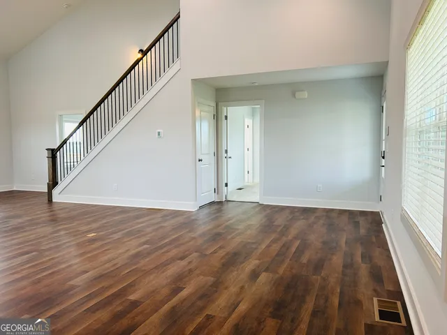 a view of an empty room with wooden floor and stairs
