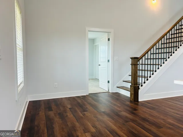a view of an empty room with wooden floor and stairs