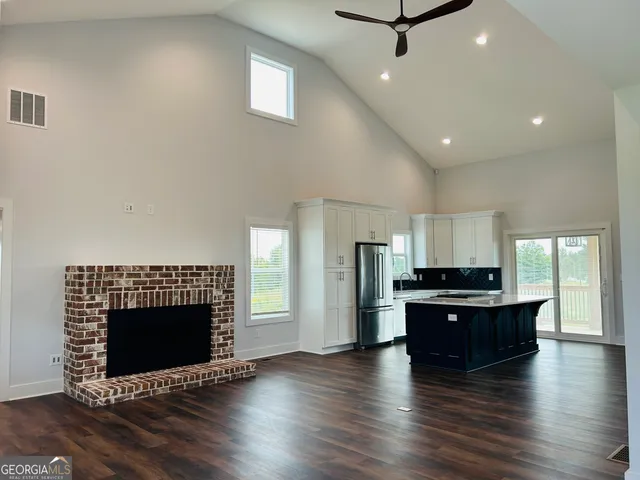 a view of a kitchen with a stove wooden cabinets and a living room
