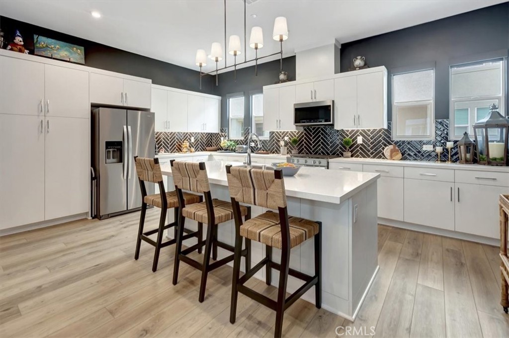 1810 West Bushell Street Anaheim, CA 92805 - Photo 12 of 36 a kitchen with stainless steel appliances a dining table chairs microwave and sink
