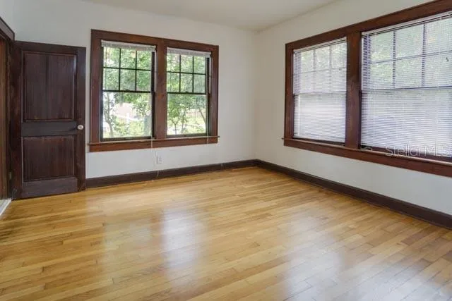 a view of an empty room with a window and wooden floor