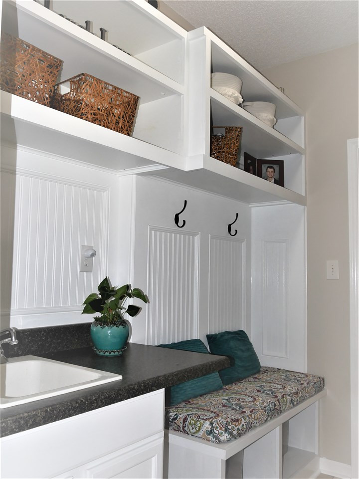 8512 Wheeling Drive Raleigh, NC 27615 - Photo 17 of 30 Custom shelving, bead board, cubbies and built-in seating with sink and cabinet, tile floors and chalk board in renovated mud room. Mud Room