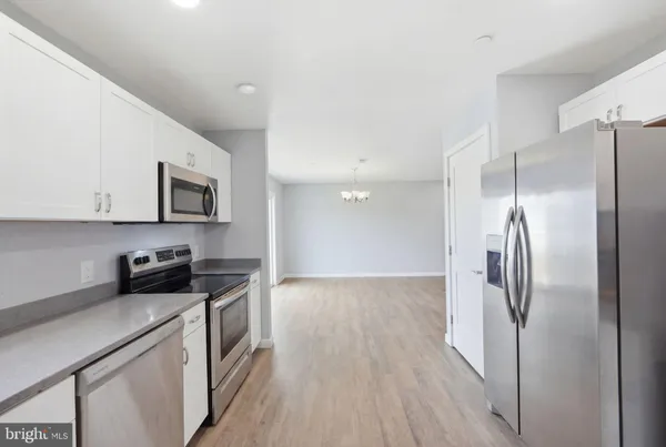 a kitchen with stainless steel appliances granite countertop a refrigerator a stove and a sink with wooden floor
