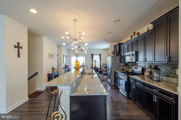 a large kitchen with sink a refrigerator and chairs
