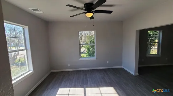 a view of an empty room with wooden floor and a window