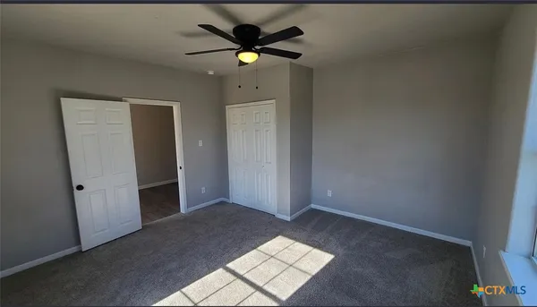 an empty room with closet and a ceiling fan