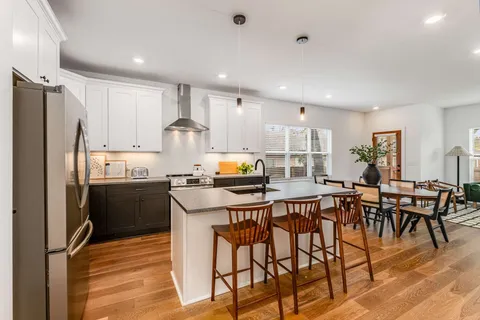a kitchen with stainless steel appliances granite countertop a table chairs refrigerator and sink