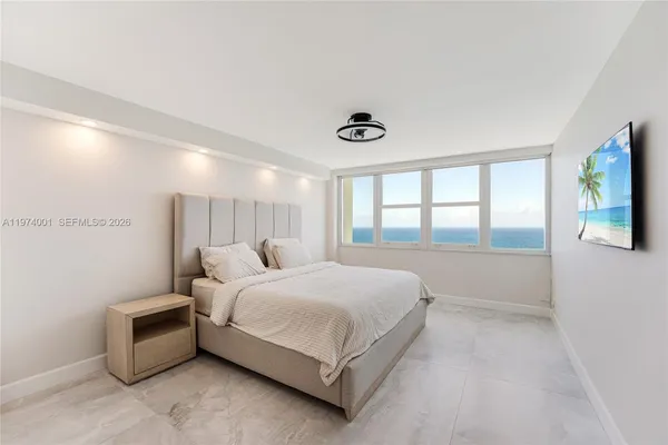 a bedroom with a large bed and a flat tv screen on dresser