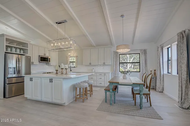 a kitchen with stainless steel appliances granite countertop a table chairs sink refrigerator and cabinets