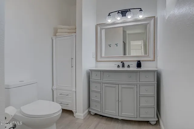 a bathroom with a toilet sink vanity and mirror