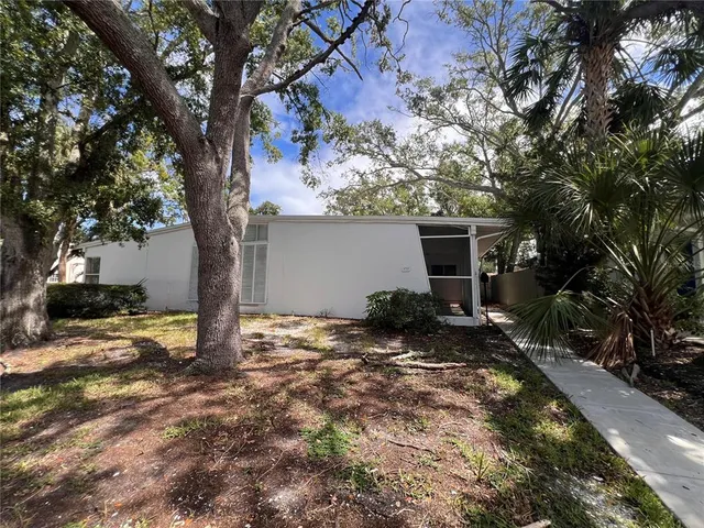 a backyard of a house with large trees and wooden fence