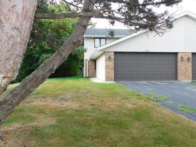 a backyard of a house with plants and large tree