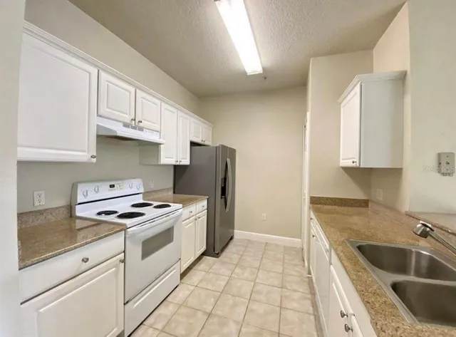 a kitchen with granite countertop a sink stove and refrigerator
