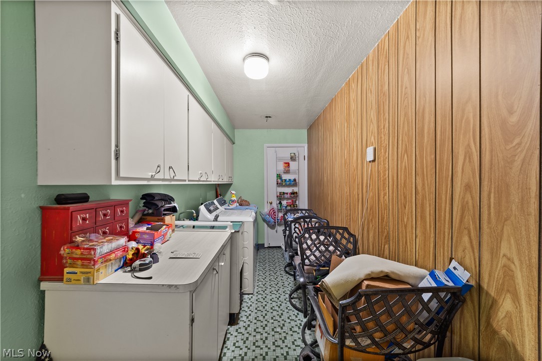 1730 Alcester Road Mayfield Heights, OH 44124 - Photo 21 of 39 Laundry room with light floors, a textured ceiling, washing machine and clothes dryer, wood walls, and cabinet space