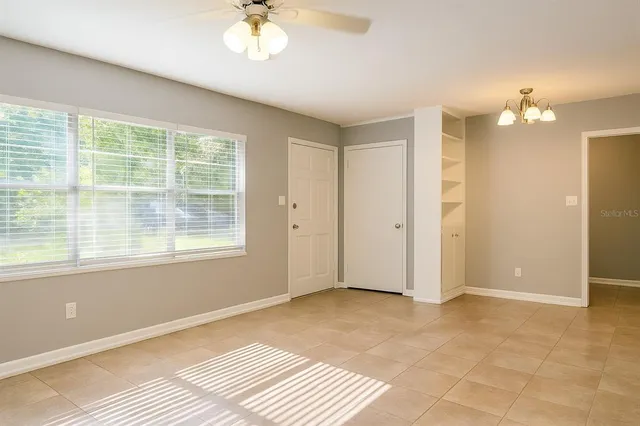 a view of a livingroom with a chandelier fan and windows