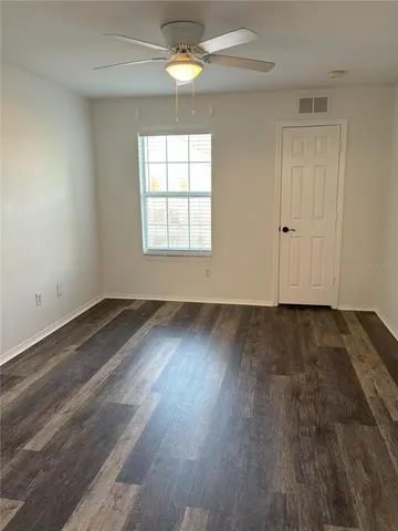 an empty room with wooden floor cabinet and windows