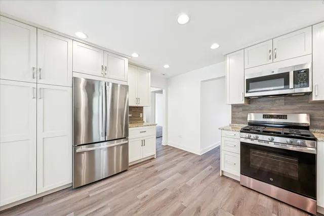 a kitchen with stainless steel appliances wooden cabinets and wooden floor