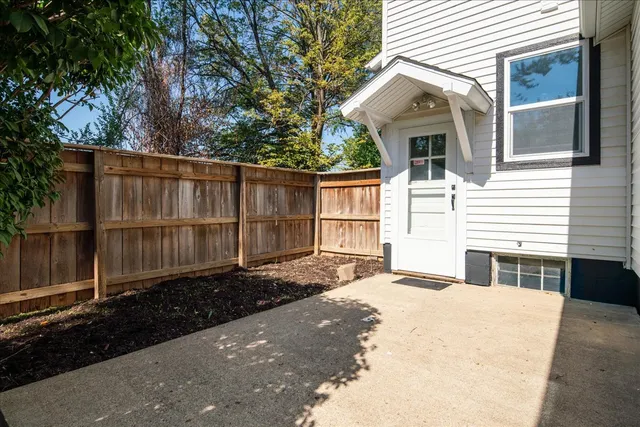 a view of a white house with large windows and wooden fence
