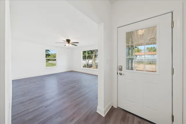 an empty room with wooden floor and windows