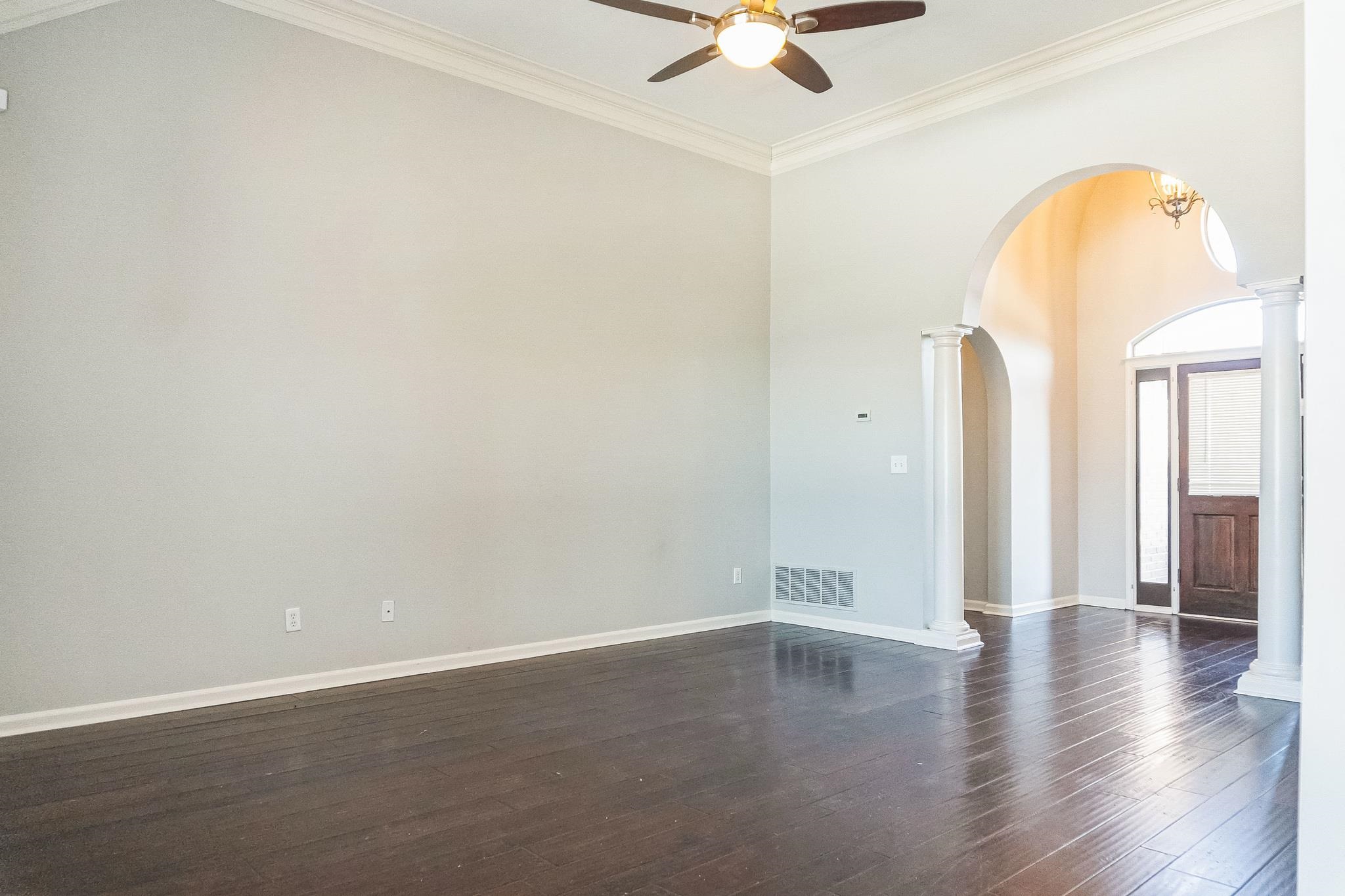 5225 Rockyford Road Bartlett, TN 38002 - Photo 3 of 18 Unfurnished room with ceiling fan with notable chandelier, dark hardwood / wood-style flooring, decorative columns, and crown molding