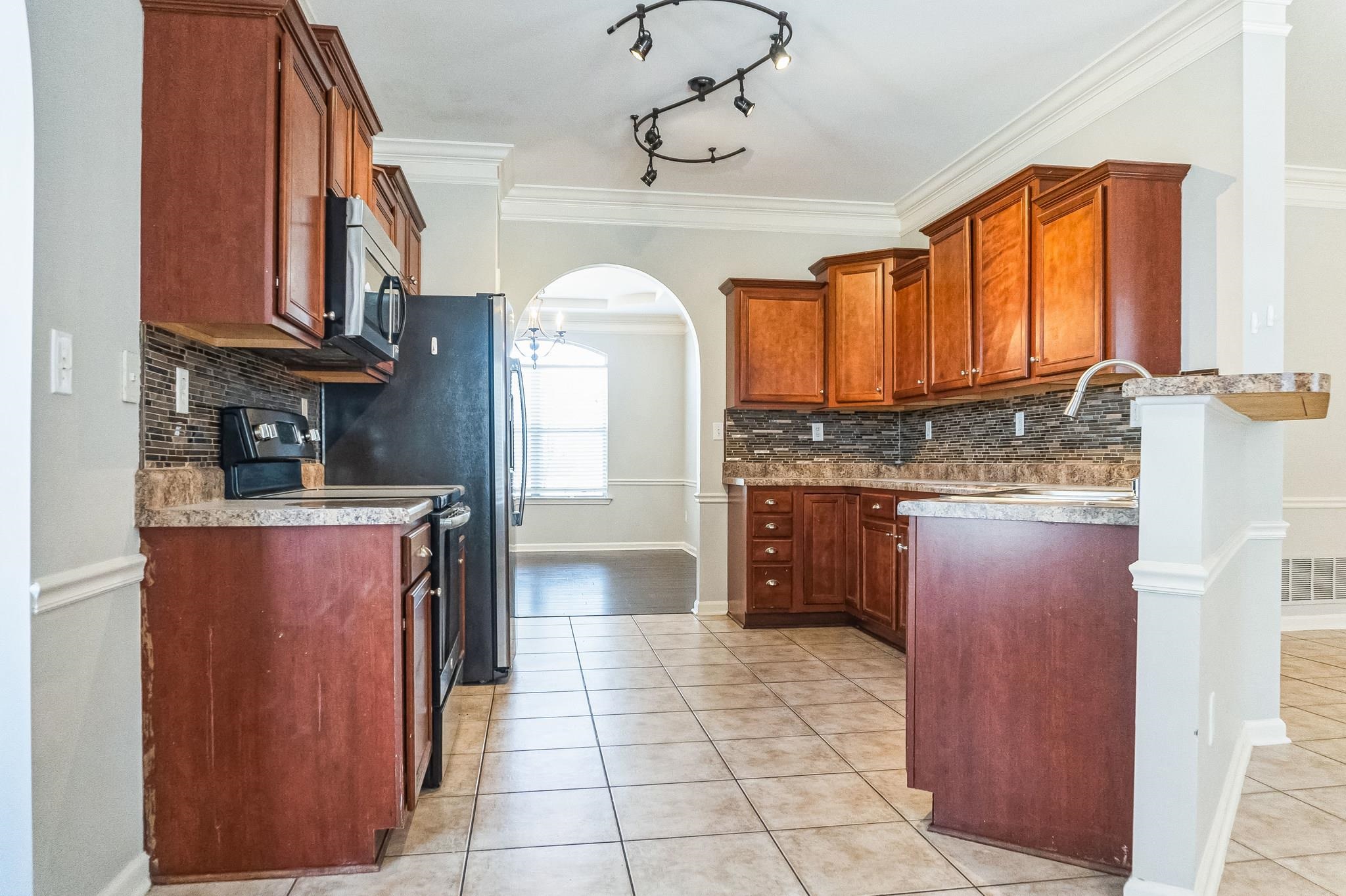 5225 Rockyford Road Bartlett, TN 38002 - Photo 9 of 18 Kitchen with range with electric cooktop, light tile patterned flooring, decorative backsplash, and crown molding