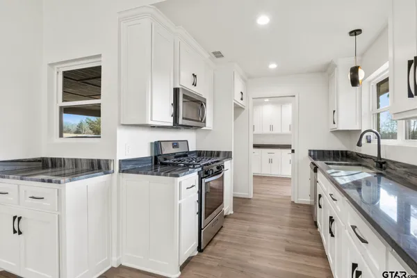a large kitchen with stainless steel appliances granite countertop a stove a sink and a microwave