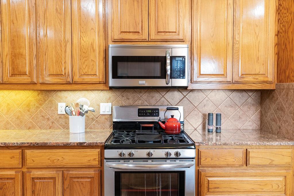 20175 Willow Glade Circle Pilot Point, TX 76258 - Photo 11 of 32 Kitchen with light stone countertops, appliances with stainless steel finishes, and tasteful backsplash
