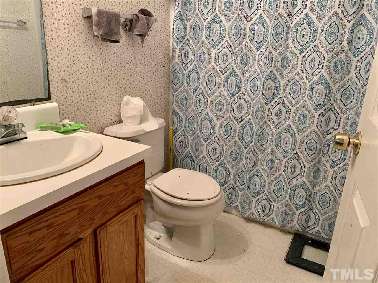 5121 Vann Street Raleigh, NC 27606 - Photo 10 of 12 a white toilet sitting next to a white sink and a shower curtain