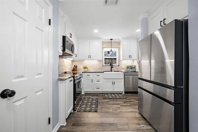 a kitchen with stainless steel appliances white cabinets sink and stove top oven