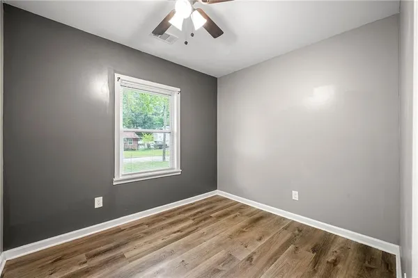 a view of empty room with wooden floor and fan