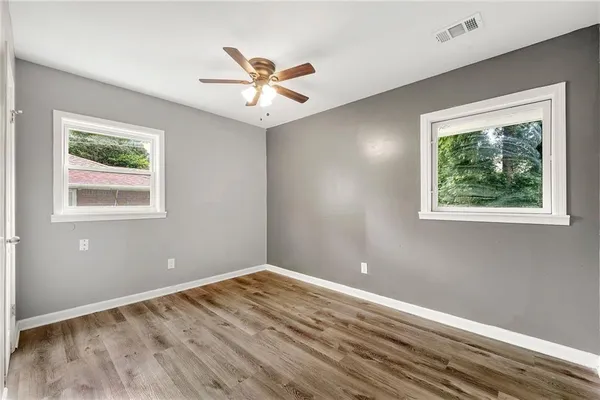 a view of a big room with wooden floor and chandelier fan