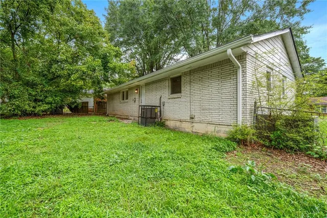 a backyard of a house with plants and large tree
