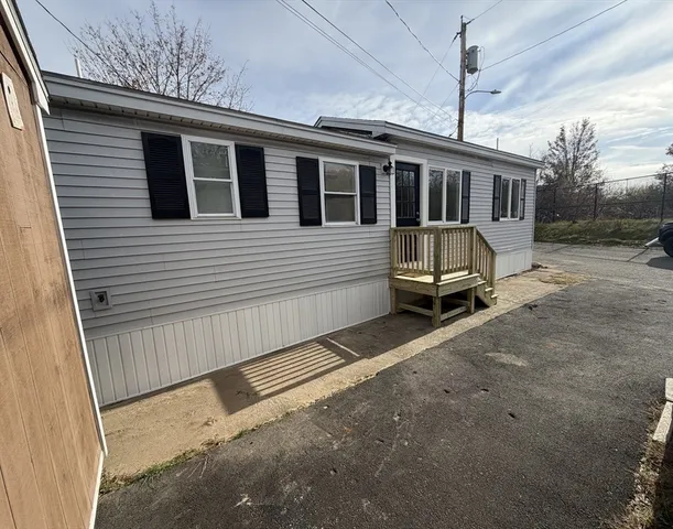 a view of a white house with a small yard and wooden fence