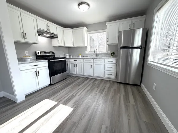 a kitchen with a refrigerator a stove top oven a sink and dishwasher with wooden floor