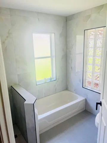 a bathroom with a bathtub and next to a window