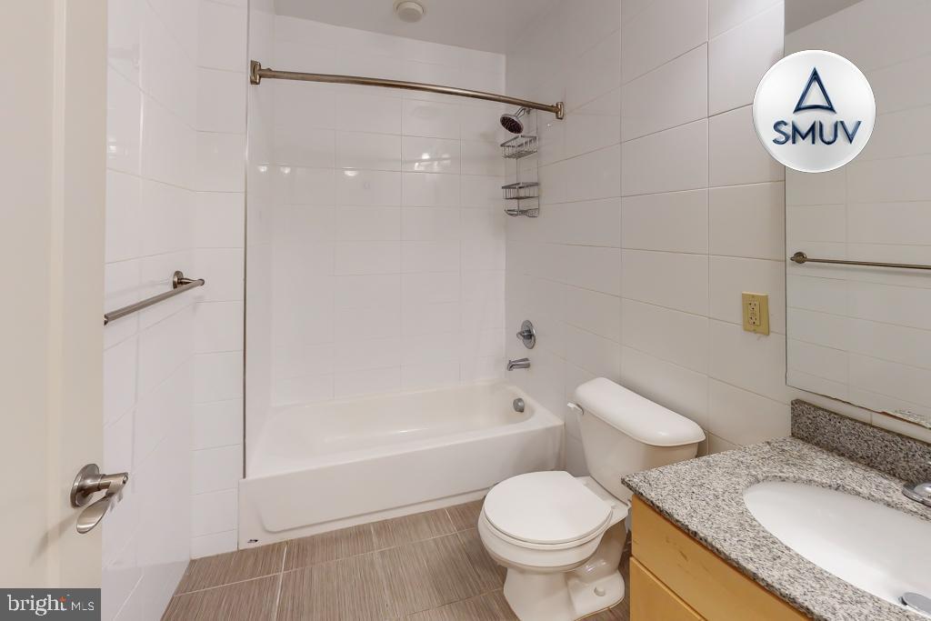 11 East Chase Street, Unit T03 Baltimore, MD 21202 - Photo 16 of 22 a bathroom with a granite countertop sink toilet a mirror and shower