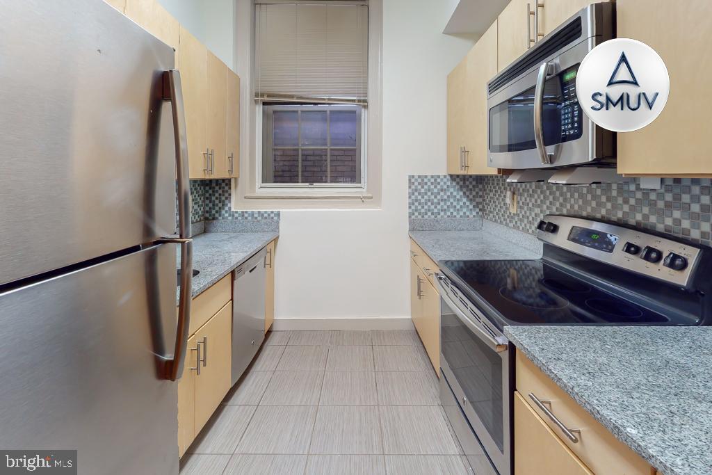 11 East Chase Street, Unit T03 Baltimore, MD 21202 - Photo 20 of 22 a kitchen with stainless steel appliances granite countertop a stove and a sink with large mirror