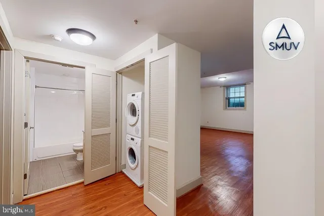 a view of a hallway with wooden floor and a bathroom