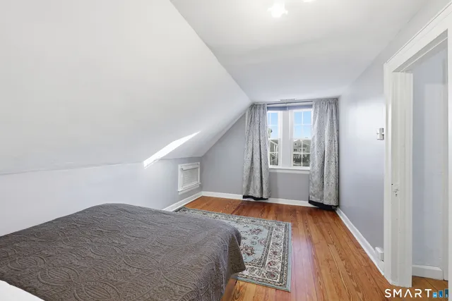 a view of a hallway with wooden floor and a bathroom